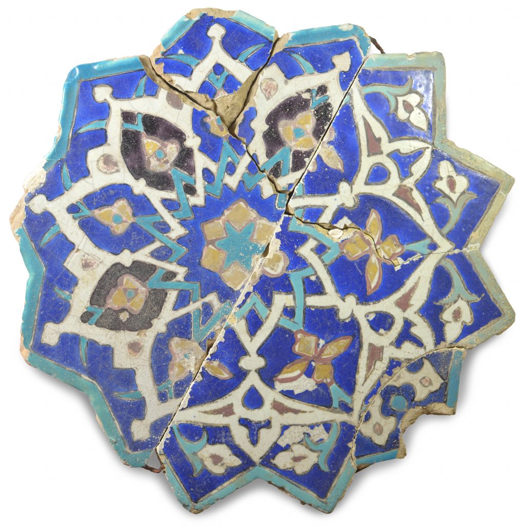 A tile in the form of a 12 pointed start with encaustic glazed decoration in blue, turquoise, gold, red, black and white